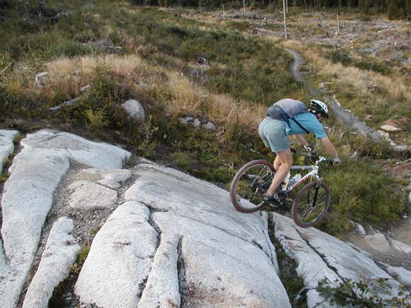 Side view of me rolling down short but steep smooth granite slab.