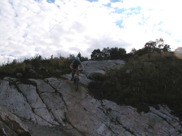 Front view of me rolling over the edge of second steep granite slab.