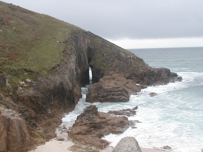 Steep hillside leading down to the sea, with narrow vertical slit cutting through it