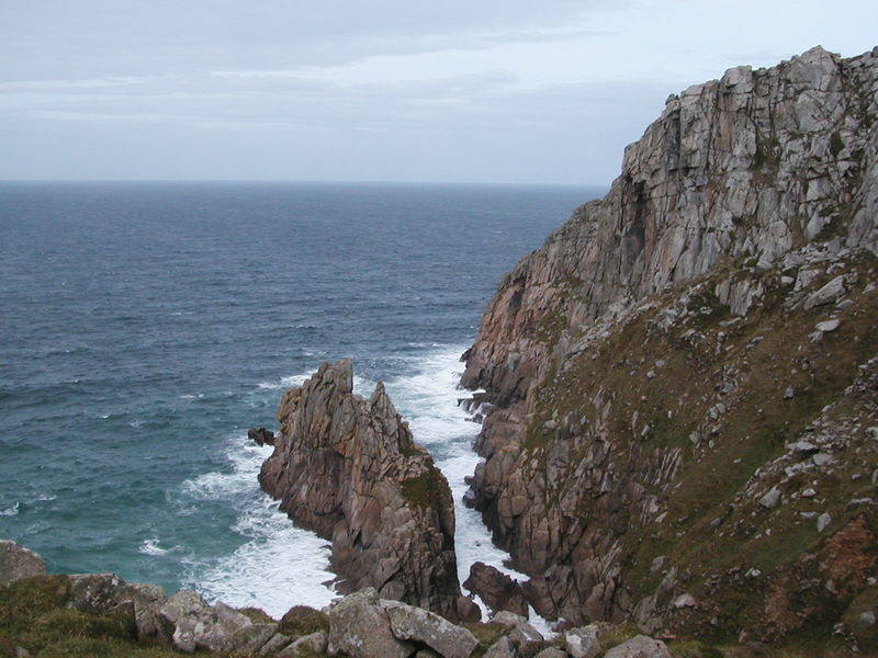 Steep cliffs of coarse grey-brown granite falling away to the sea below.