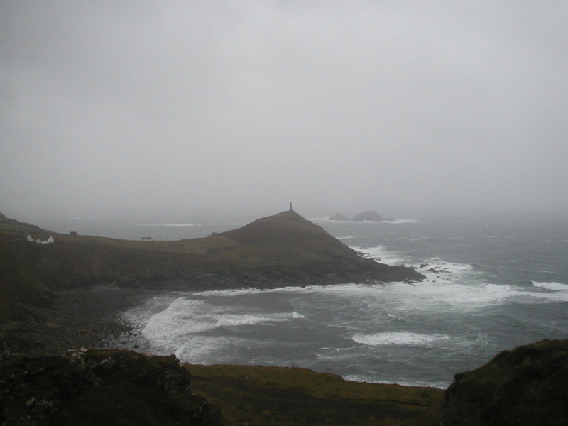 Small headland surrounded by rough sea with a tower on the peak of it.