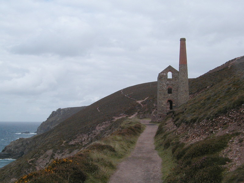 Tall old ruined building with distinct cylindrical chimney, blue skies with fluffy clouds behind