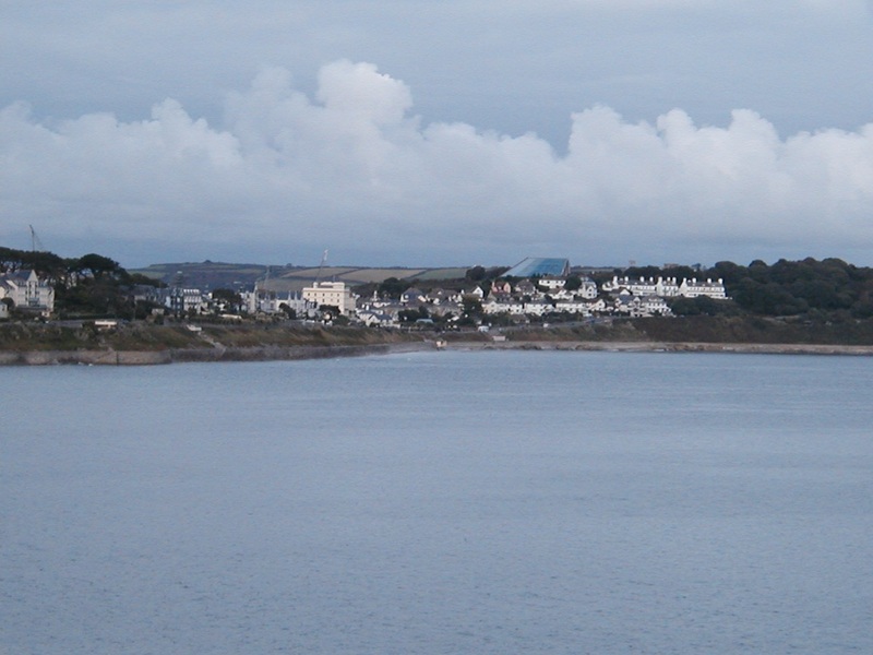 Looking across sea to lots of white houses and buildings, bank of cloud in background