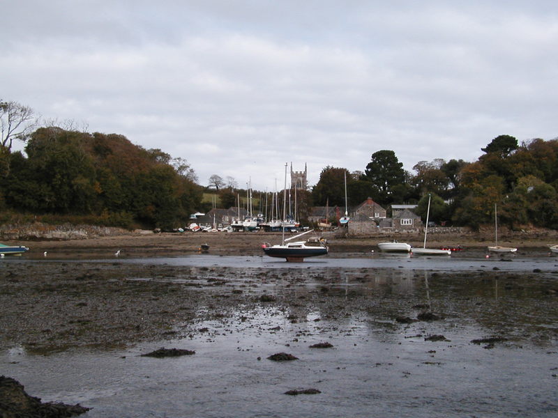 Looking across an almost dried up tidal inlet towards a few houses and a church.