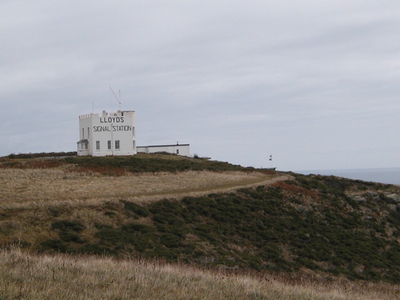 Small square white building with 'Lloyds signal Station' written on the side