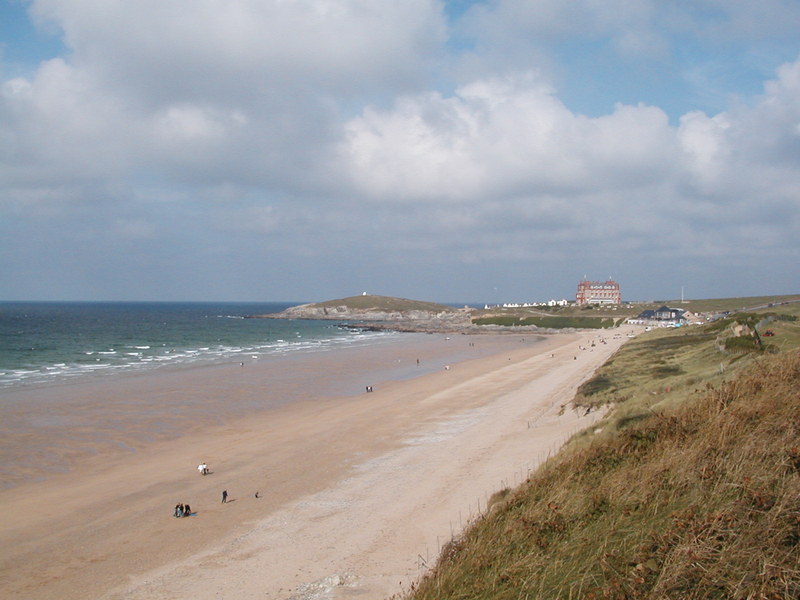 Wide sandy beach with large hotel on headland in background