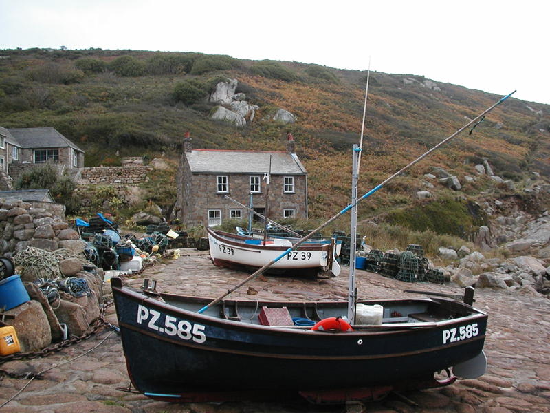 Three small boats on a slipway with small cottage behind.