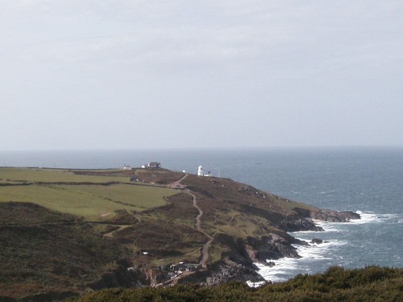Headland with top of a lighthouse visible and narrow tracks winding its way towards it