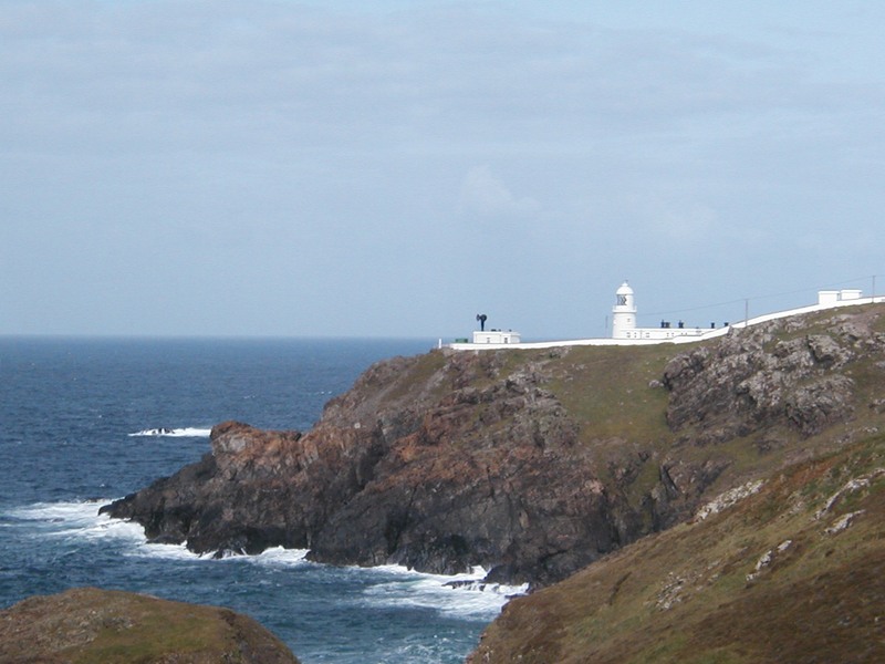 Small white lighthouse and buildings on rocky headland