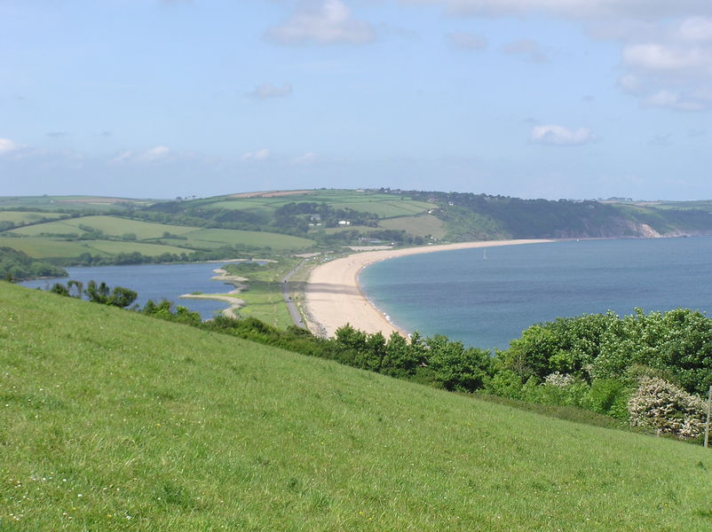 Looking across grass hillside, along strip of sand with sea on one side, and lake on the other.